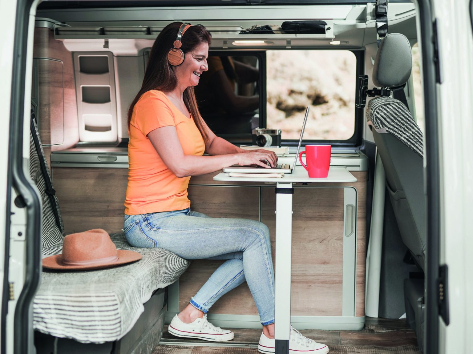 Happy mature woman using computer laptop inside mini van camper