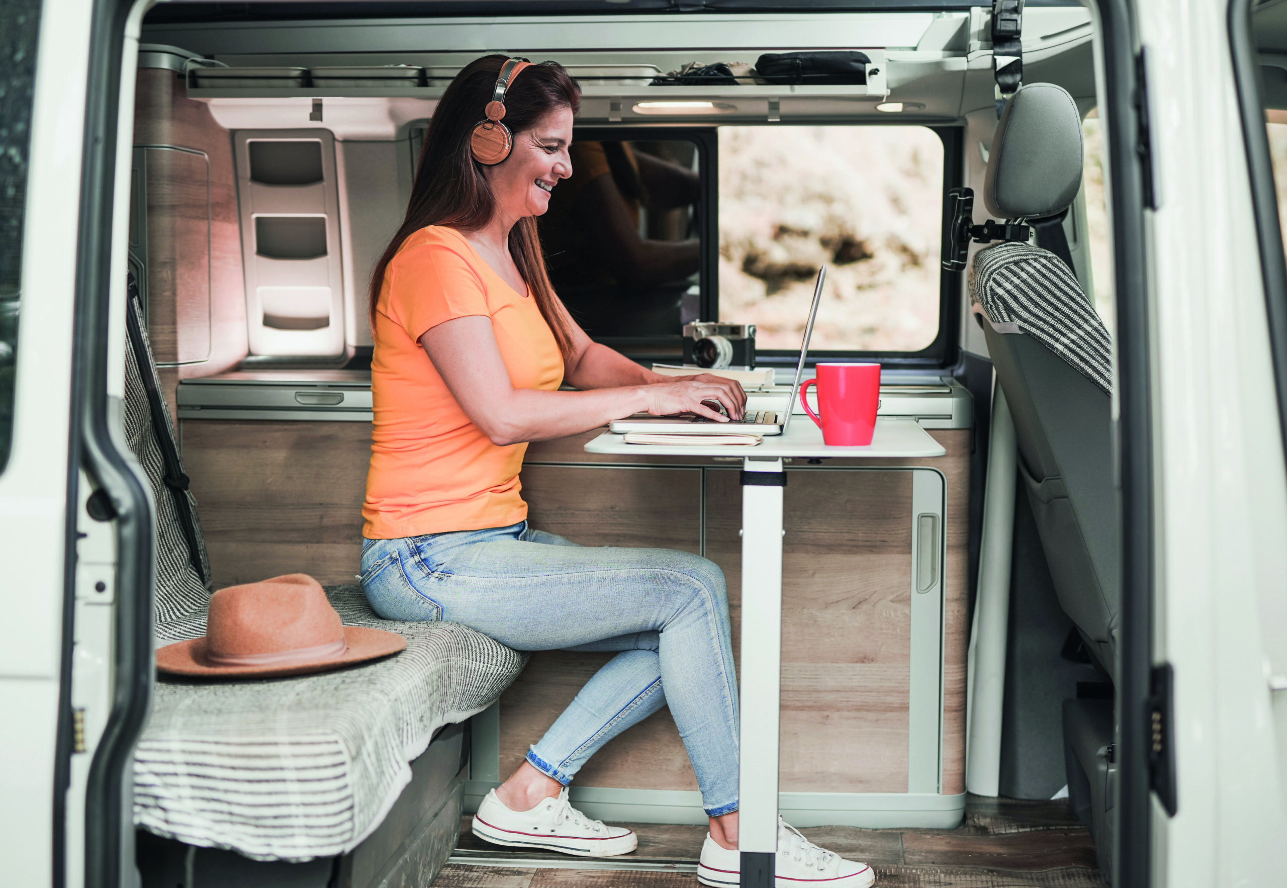 Happy mature woman using computer laptop inside mini van camper